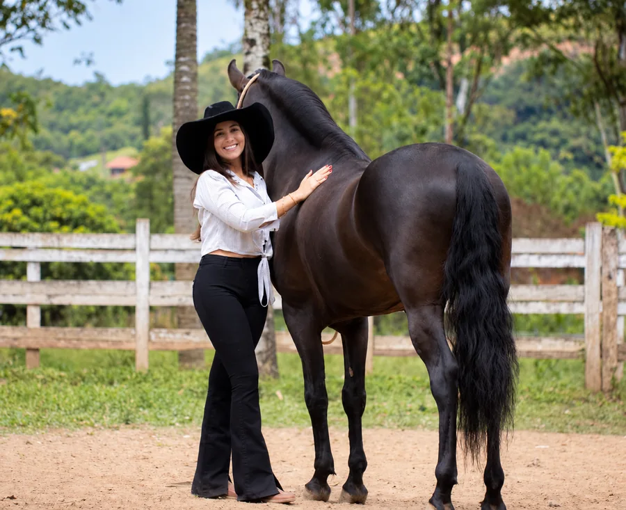Camila Oliveira ao ar livre Camila Oliveira ao lado de um cavalo preto